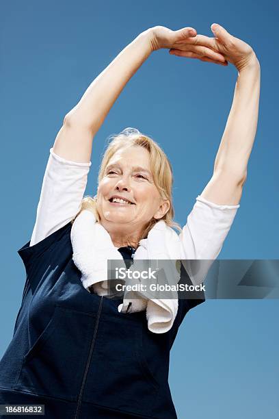Foto de Feminino Alongando Suas Mãos Com Uma Toalha Ao Redor Da Gola e mais fotos de stock de 50-54 anos