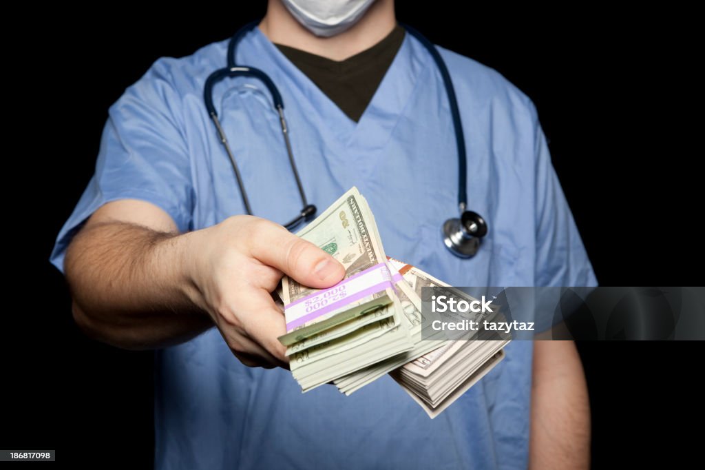 Surgeon handing over money Surgeon in blue scrubs handing over stacks of cash. Debt Stock Photo