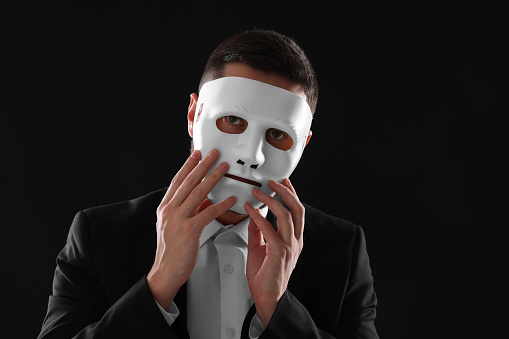 Multiple personality concept. Man in mask on black background