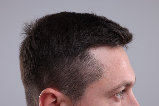 Man with healthy hair on grey background, closeup
