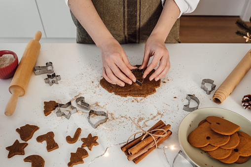 woman cutting out gingerbread cookies from the dough for christmas