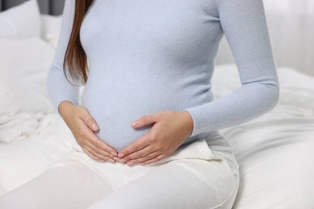 istock Pregnant woman on white bed, closeup view 1868184295