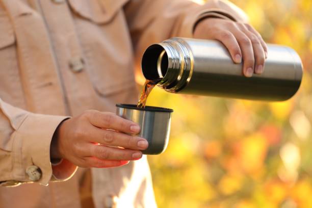istock Woman pouring tea from thermos into cup lid outdoors, closeup 1868187424