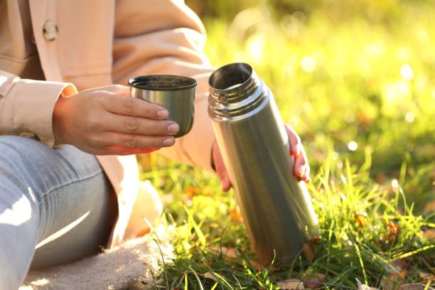 istock Woman with thermos and cup lid on green grass outdoors, closeup. Space for text 1868189802
