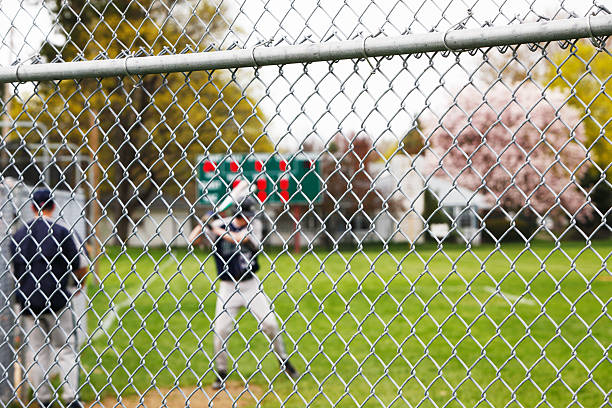 giocatore di baseball oscillare la maglia da riscaldamento oltre rete metallica - high school baseball foto e immagini stock