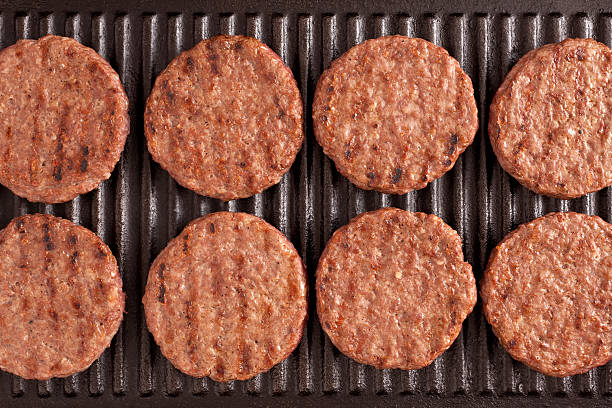 Four raw meat burger patties in retail packaging - white background