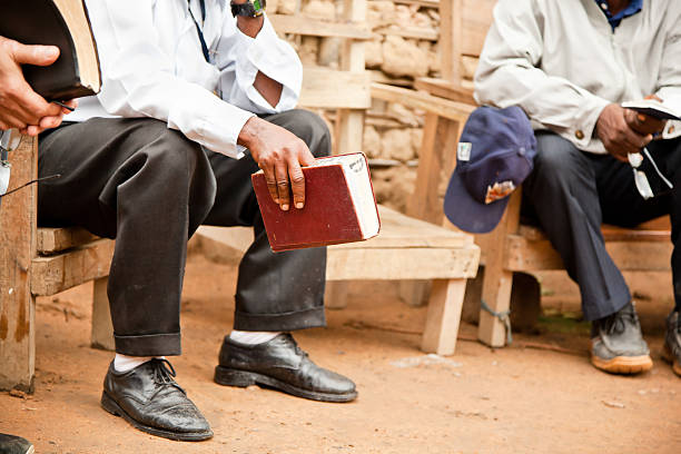A man holding the bible and sitting on a park bench