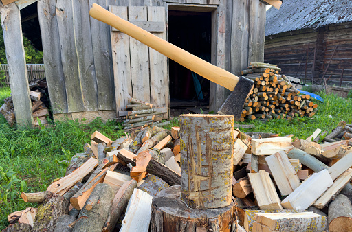Firewood for heating the stove in house. Preparation of firewood in village for heating the house in winter. Lumberjack axe for chopping timber.