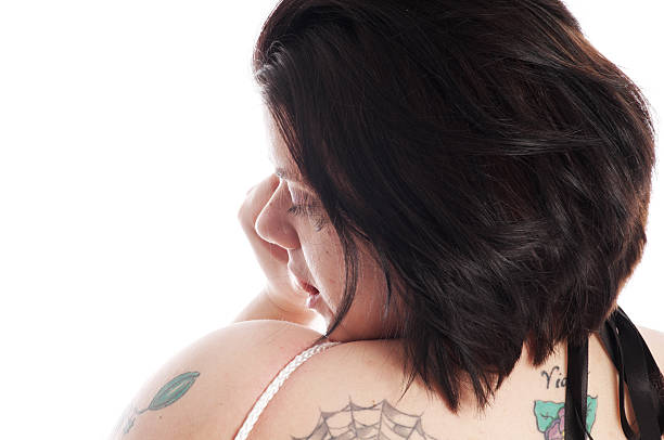 Profile of young woman biting thumb. "Young woman with tattoos and rope visible, biting thumb. Horizontal studio shot on white" Tied Up Bondage Women Fetish Wear stock pictures, royalty-free photos & images