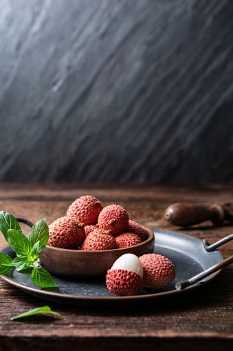 Bowl of ripe tropical lichee fruit (Litchi chinensis) on wooden background