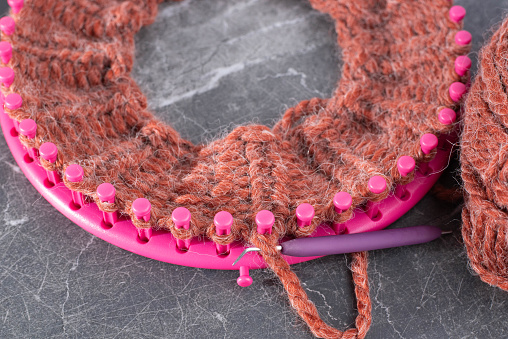 Knitting loom with a soft, fuzzy, chunky yarn with both knit and pearl stitches.