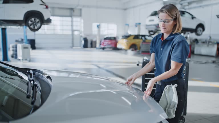 Female mechanic examining,fixing car engine in repair shop