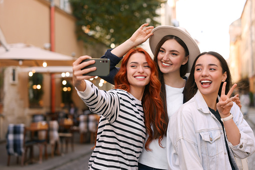 Happy friends taking selfie on city street