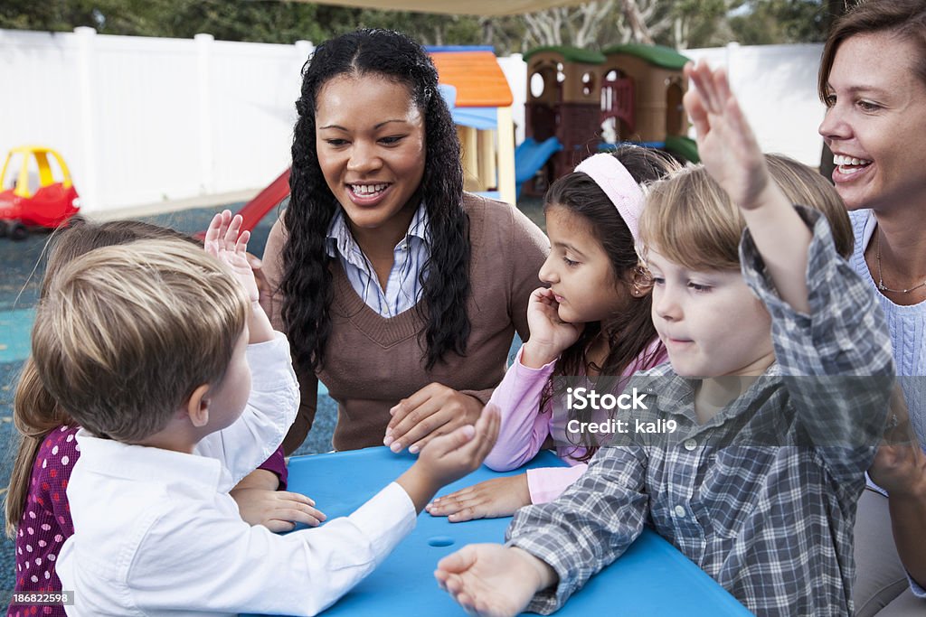 Enfants avec l'enseignant de garde d'enfants sur l'aire de jeux - Photo de Maternelle libre de droits