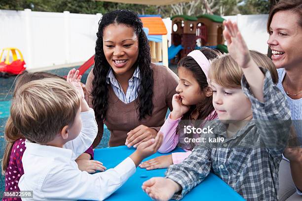 Photo libre de droit de Enfants Avec Lenseignant De Garde Denfants Sur Laire De Jeux banque d'images et plus d'images libres de droit de Maternelle