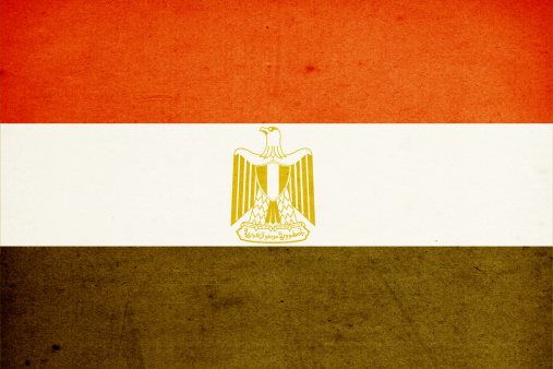 The national flag of Egypt, a tricolour consisting of the three equal horizontal red, white, and black bands, The flag bears Egypt's national emblem, the Egyptian eagle of Saladin in the white band, selective focus