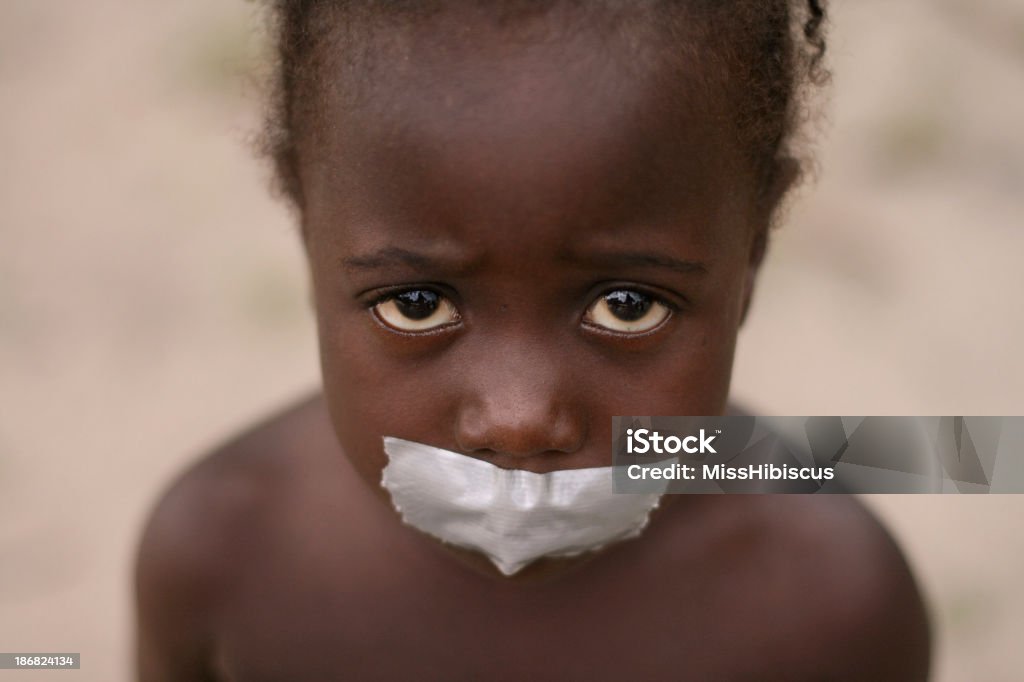 African Girl with Tape on Mouth A sad African girl with tape covering her mouth. Signifies needy or oppressed children with the inability to speak up and defend themselves. Slavery Stock Photo