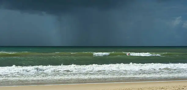 "Noosa's Main Beach bay, a paradise for surfers and families with kids.Today the dark rain clouds are passing by  very close to the beach and empty themselves"