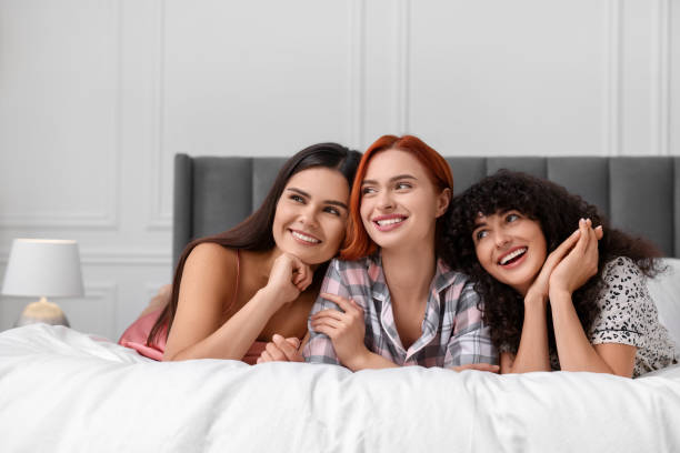 istock Happy young friends on bed at home 1868242502