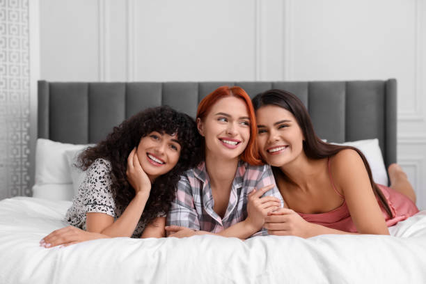 istock Happy young friends on bed at home 1868244752