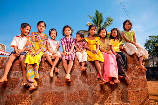 Group of Cheerful Rural Indian Children Sitting on a Wall
