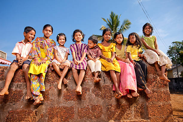 Group of Cheerful Rural Indian Children Sitting on a Wall Group of Cheerful Rural Indian Children Sitting on a Wall indian boy barefoot stock pictures, royalty-free photos & images