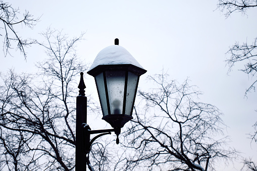 Lantern on the street in winter. Retro style street lamp covered with snow during the day