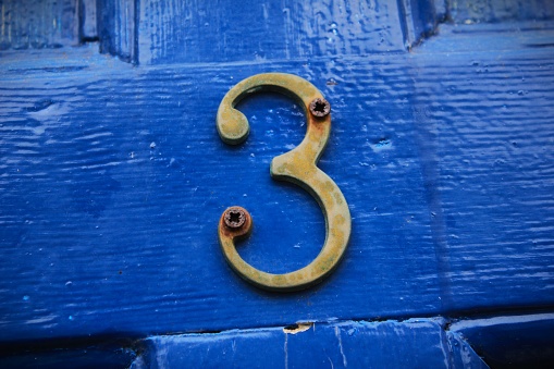 Door number 3 on the blue background of an old door