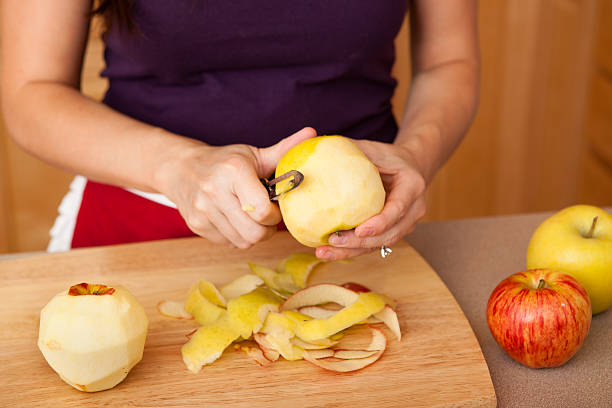 istock Young Woman Peeling Apples in Kitchen at Home 186827514