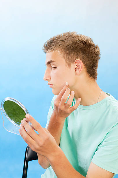 Teenage boy applying cleaning patch to a pimple. Handsome teenage boy applying cleaning patch to a pimple. one eyed stock pictures, royalty-free photos & images