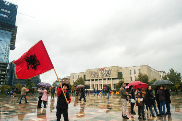 mann schwenkt große albanische flagge im nationalen geschichtsmuseum am unabhängigkeitstag - flag waving weather rain stock-fotos und bilder