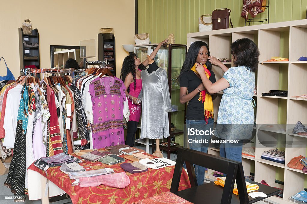Salesperson Assisting Clothes Shopper Salesperson assisting a shopper with a scarf in a boutique store.  Another woman is shopping in the background.Click below for more of my shopping and retail images: Adult Stock Photo