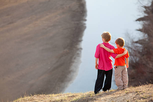 Two boys admiring a beautiful river and wetlands view. Spring. Horizontal colour image.