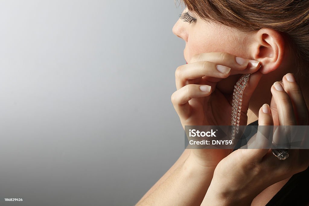 Earring A woman putting on an earring. Getting Dressed Stock Photo