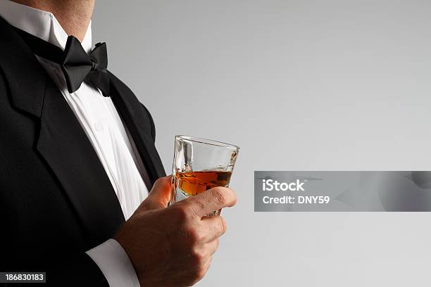 Człowiek W Smoking Trzymając Kieliszek Whisky Strzał Na Szarym Tle - zdjęcia stockowe i więcej obrazów Alkohol - napój