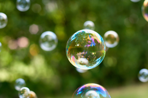 Lots of soap bubbles flying in the air. Focus on one big bubble in the middle of the photo.