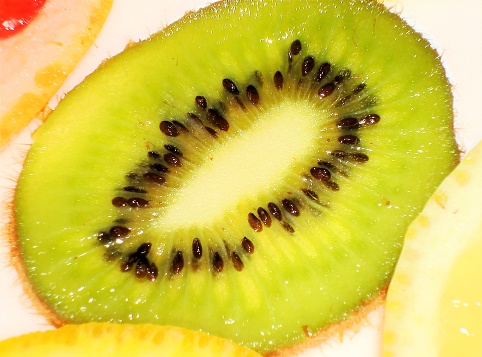 Green and yellow kiwi fruits on a plate top view