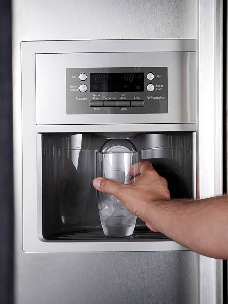 Getting glass of filtered water from refrigerator. Hand reaching a glass under the filtered water dispenser on a modern stainless steel refrigerator.Please see some similar pictures from my portfolio: ice machines stock pictures, royalty-free photos & images