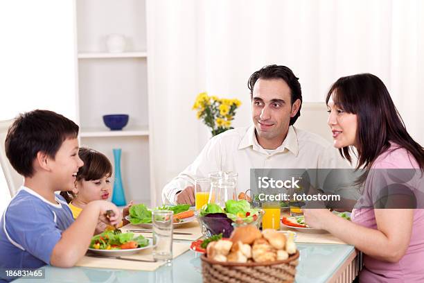 Feliz Familia Comiendo Verduras Para La Cena Juntos Foto de stock y más banco de imágenes de Adulto
