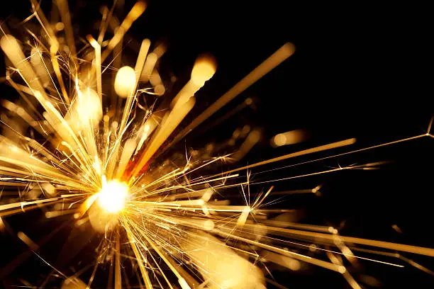 Photo of A close up shot of a yellow sparkler with black background 