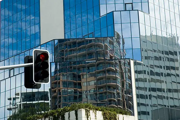 Traffic lights on red with tall glassy office building in the background