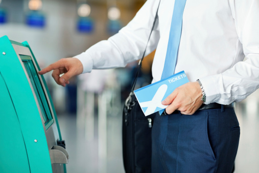 Cropped image of businessman standing by a self-service check-in at the airport. Horizontal shot.