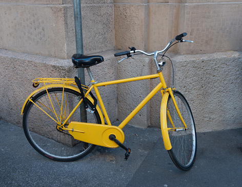 Yellow bicycle tied to the pole to prevent theft