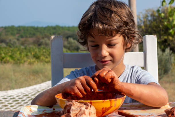 istock Boy playing with ceramic clay. He works for his creativity. A 9-year-old boy playing with ceramic clay in a bowl. He works at the table on the porch of the house. 1868345409