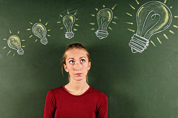 istock Young Woman Looking at Sketched Light Bulbs 186834766