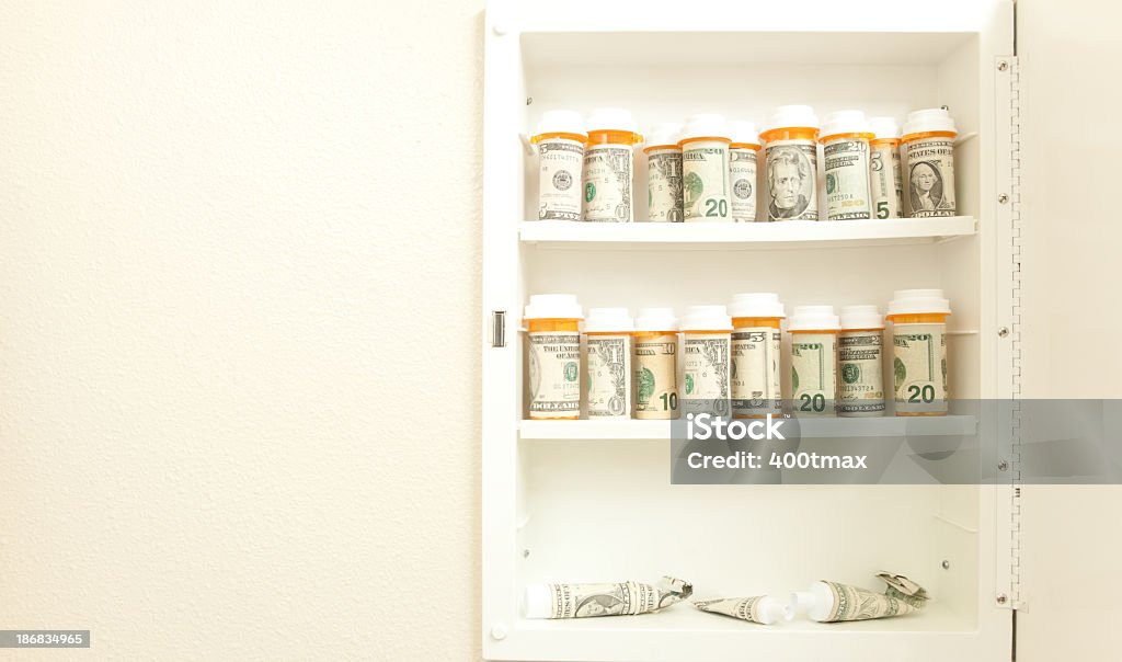 Medicine cabinet Prescription bottles and tube wrapped in currency in a medicine cabinet. Ointment Stock Photo