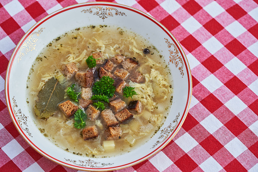 Close up picture of delicious and healthy garlic soup, dish from cuisine of Czech republic made from beef broth, potatoes, eggs and fresh garlic, served with parsley and bread crums mainly in winter.