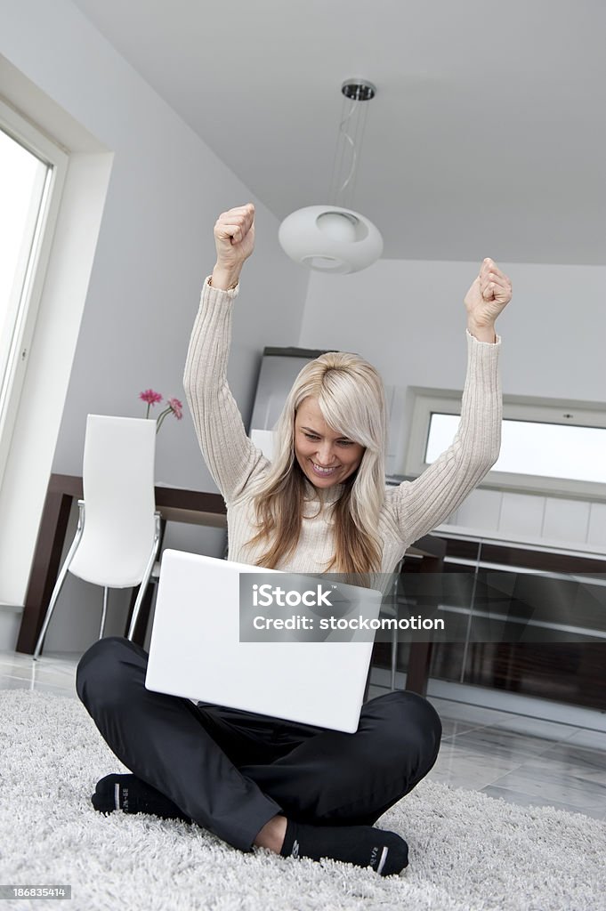 Beautiful young woman cheering A young woman looking at her laptop and cheering.You might also like: 20-29 Years Stock Photo