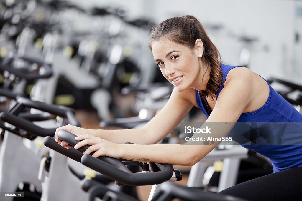 Mujer joven en una clase de ciclismo - Foto de stock de Bicicleta estática libre de derechos