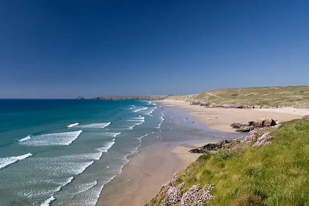 Perranporth beach on the north coast of Cornwall in South West England. It is a beautiful sunny day and waves are rolling into sea shore.